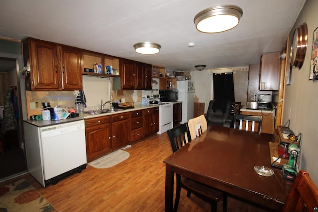 kitchen with light wood-type flooring, tasteful backsplash, sink, and white appliances