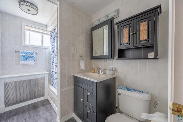 full bathroom featuring radiator, tile walls, shower / bath combination with curtain, and hardwood / wood-style flooring