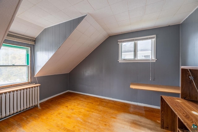 bonus room featuring radiator, a wealth of natural light, lofted ceiling, and light hardwood / wood-style floors