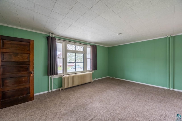 empty room featuring carpet flooring, crown molding, and radiator