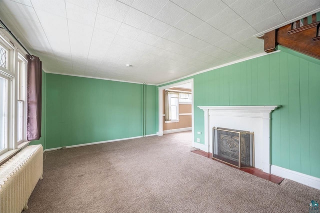 unfurnished living room with carpet floors, crown molding, and radiator