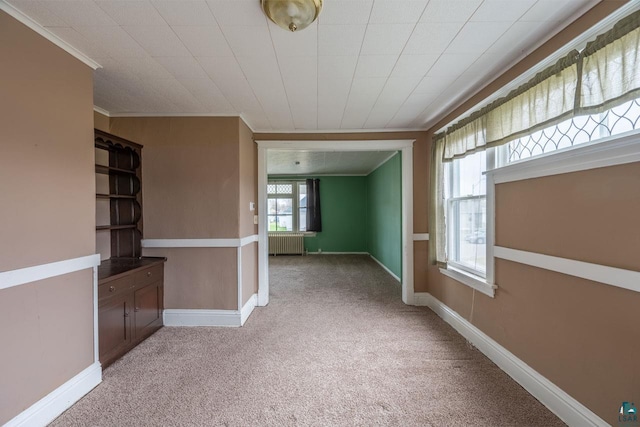 carpeted spare room with radiator heating unit and crown molding