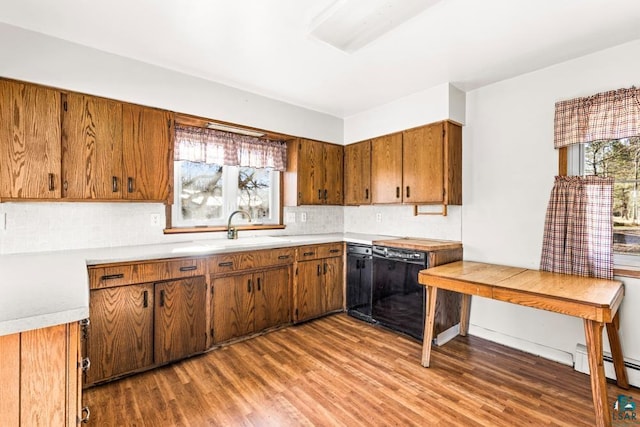 kitchen with a baseboard radiator, black dishwasher, light countertops, dark wood-style floors, and tasteful backsplash