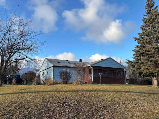 rear view of property with a sunroom and a lawn