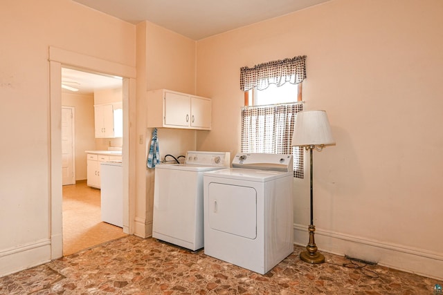 clothes washing area featuring cabinets and separate washer and dryer