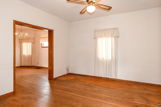 spare room with ceiling fan with notable chandelier and hardwood / wood-style flooring