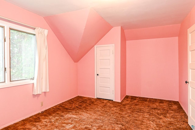 additional living space with dark carpet and vaulted ceiling