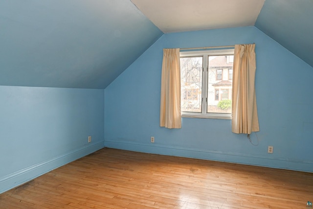 additional living space with light hardwood / wood-style flooring and lofted ceiling