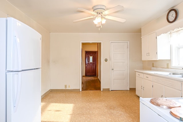 kitchen with ceiling fan, white fridge, white cabinetry, and sink