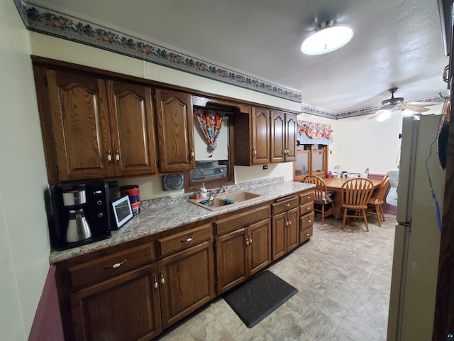 kitchen featuring ceiling fan, white refrigerator, dark brown cabinets, and sink