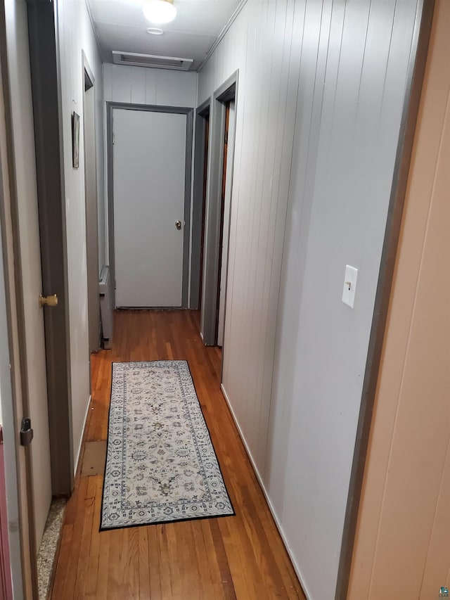 hall with hardwood / wood-style flooring and wood walls