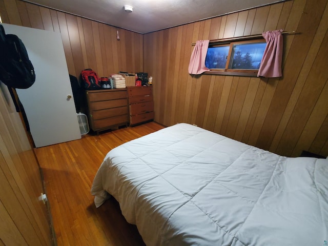 bedroom with wood walls and wood-type flooring