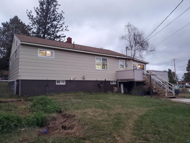 rear view of property featuring a lawn and a deck