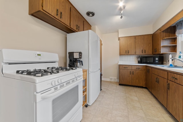 kitchen featuring rail lighting, white appliances, sink, and tasteful backsplash