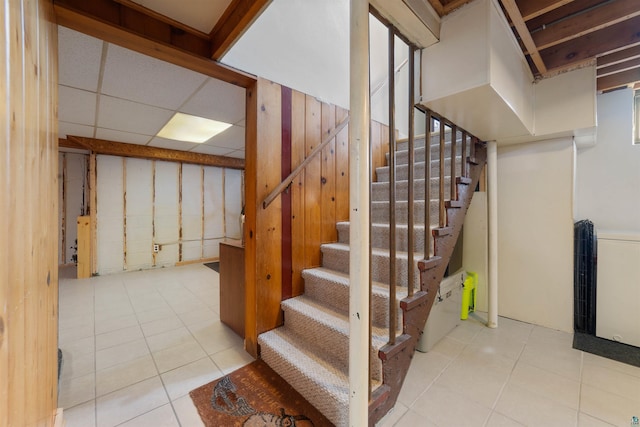 basement featuring a paneled ceiling and light tile patterned floors