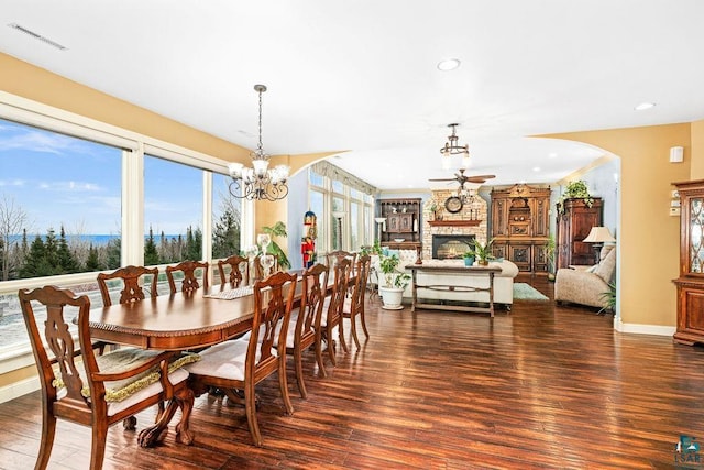 dining area with a fireplace, ceiling fan with notable chandelier, and dark hardwood / wood-style floors