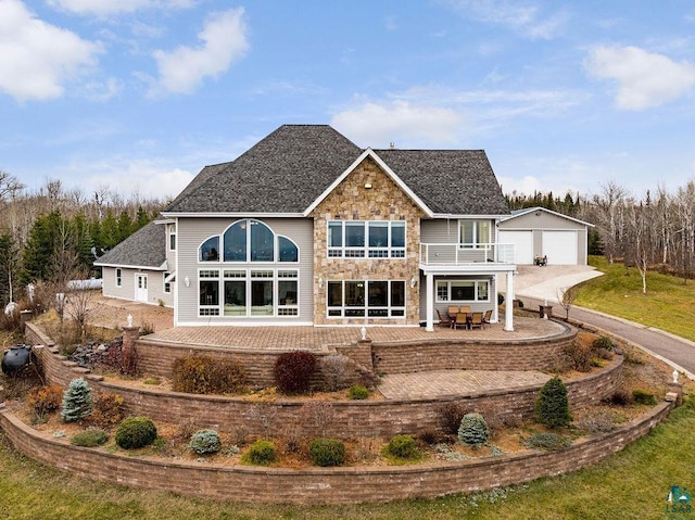 rear view of house featuring a balcony, an outdoor structure, a garage, and a patio area