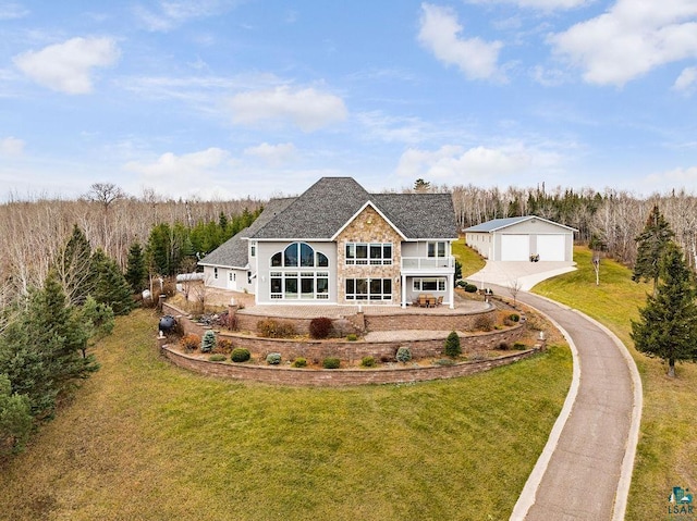 back of property with a lawn, an outbuilding, a balcony, and a garage