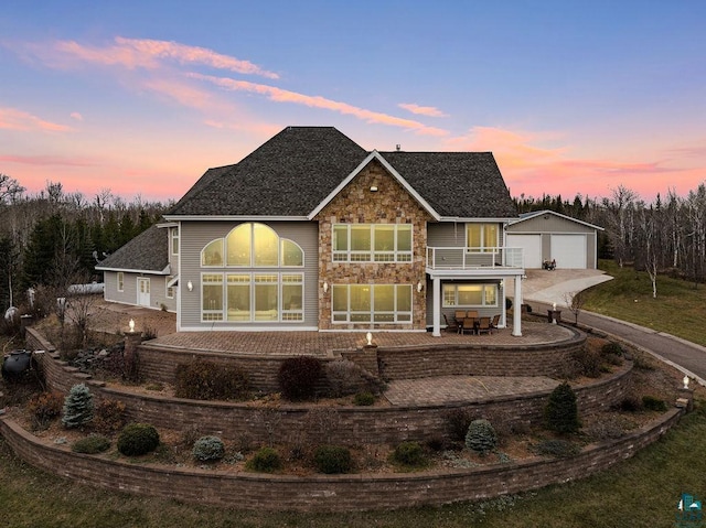 view of front facade with a garage, an outdoor structure, a balcony, and a patio