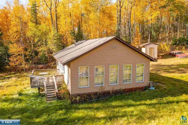 view of home's exterior with a wooden deck, a yard, and a storage shed