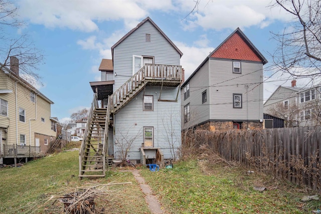 rear view of property featuring a balcony and a yard