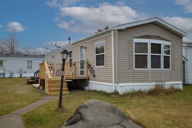 manufactured / mobile home with a deck and a front lawn