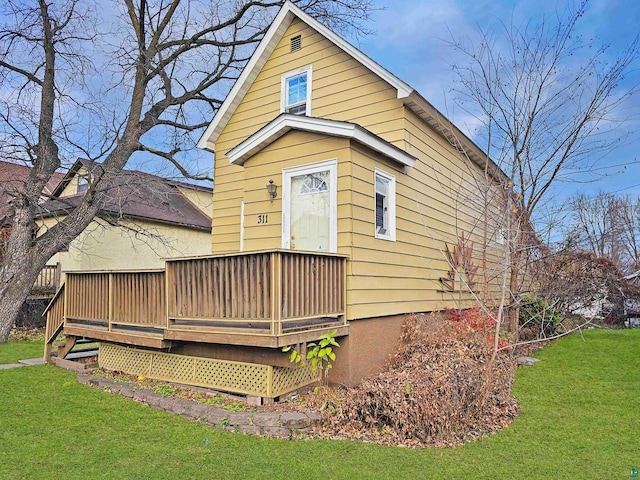 back of house with a deck and a lawn