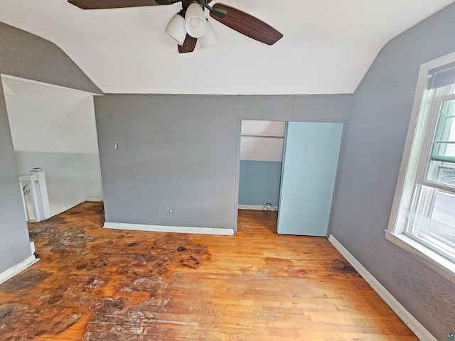 empty room with ceiling fan, light hardwood / wood-style flooring, and vaulted ceiling