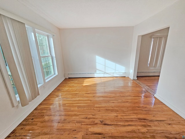 unfurnished room with light wood-type flooring, a textured ceiling, and a baseboard heating unit