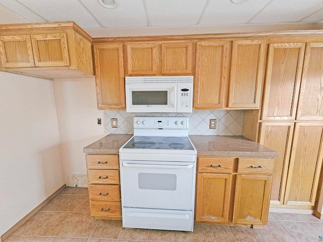 kitchen featuring decorative backsplash, a drop ceiling, light tile patterned floors, and white appliances