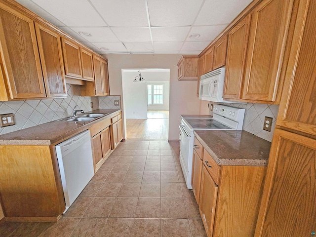 kitchen with white appliances, backsplash, sink, a notable chandelier, and light tile patterned flooring