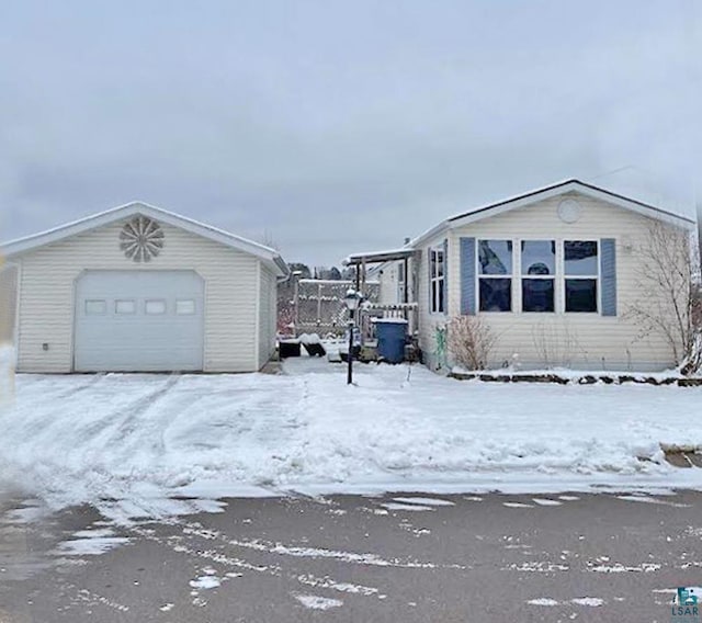 snow covered property with a garage and an outbuilding