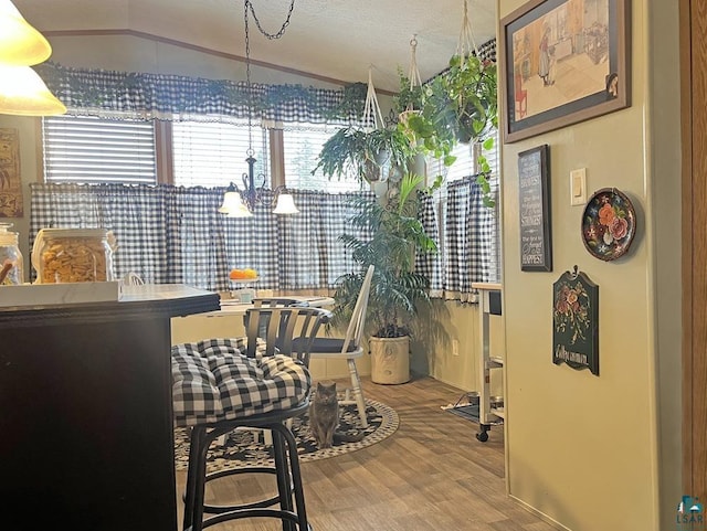 dining space with a chandelier, a textured ceiling, hardwood / wood-style flooring, and lofted ceiling