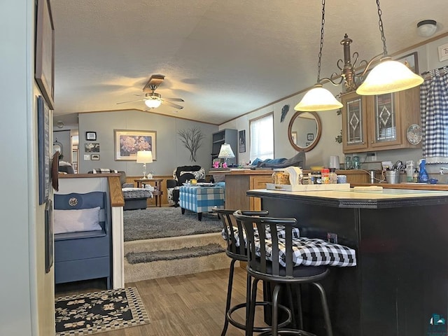 kitchen featuring hardwood / wood-style floors, a kitchen breakfast bar, a textured ceiling, and vaulted ceiling