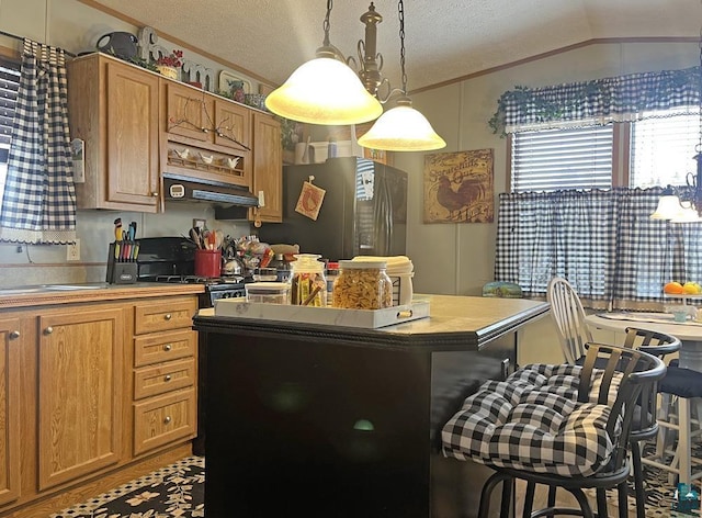 kitchen with a kitchen breakfast bar, a textured ceiling, vaulted ceiling, decorative light fixtures, and stainless steel refrigerator