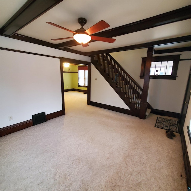 interior space featuring ceiling fan, beamed ceiling, and light colored carpet