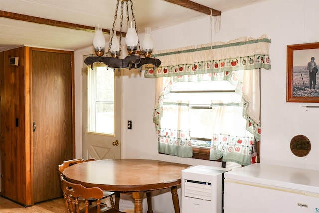 dining room featuring wooden walls, light wood-type flooring, and a notable chandelier