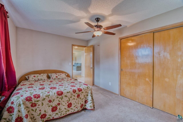 bedroom with ceiling fan, light colored carpet, a textured ceiling, and a closet