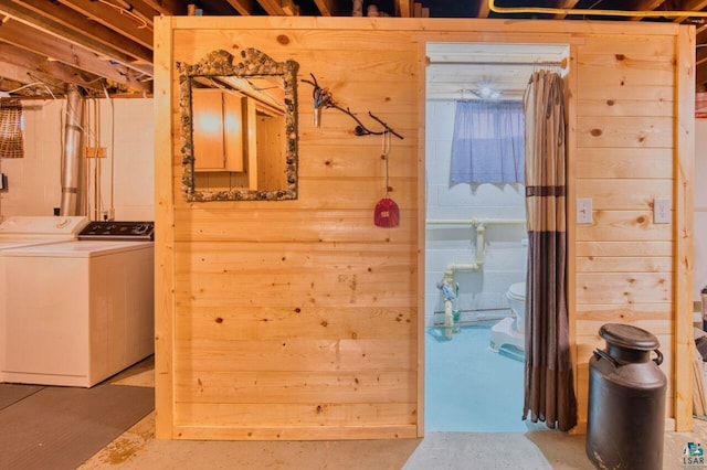 clothes washing area featuring washing machine and dryer and wood walls