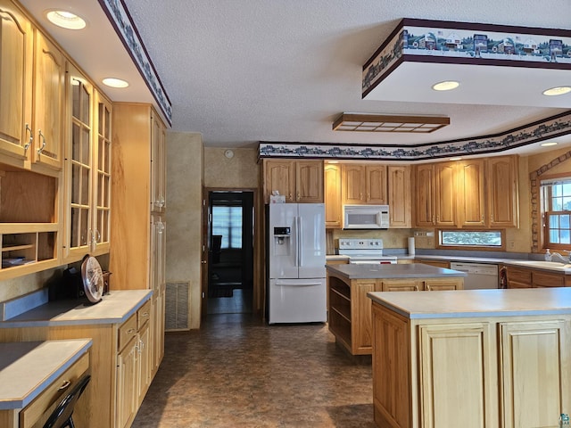 kitchen with a textured ceiling, white appliances, a kitchen island, and sink