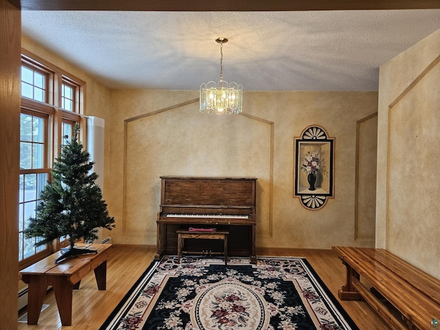 living area with wood-type flooring, a textured ceiling, and an inviting chandelier