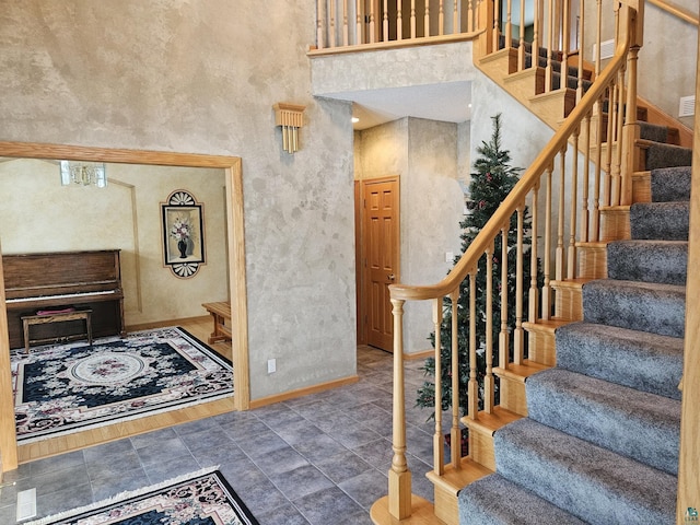 stairway featuring wood-type flooring and a towering ceiling