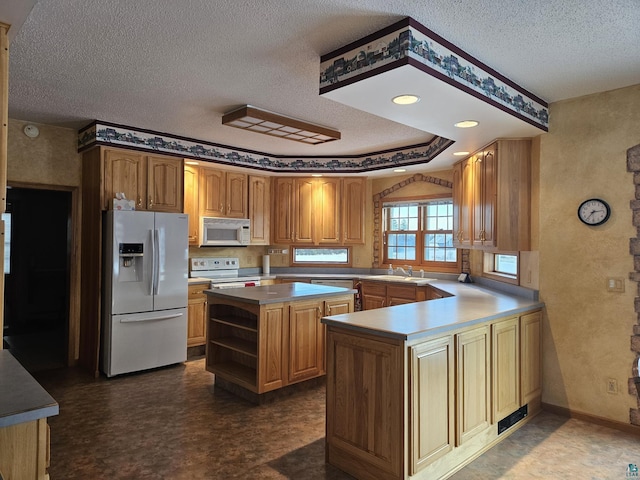 kitchen featuring a textured ceiling, white appliances, a center island, and sink