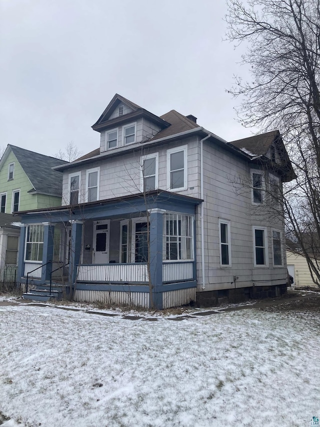 snow covered house featuring a porch