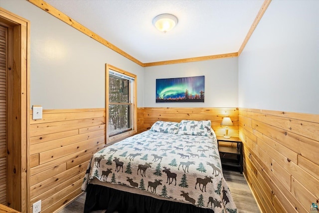 bedroom featuring wood walls, wood-type flooring, and ornamental molding