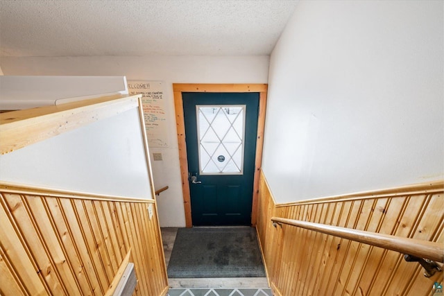 entryway featuring wood walls and a textured ceiling