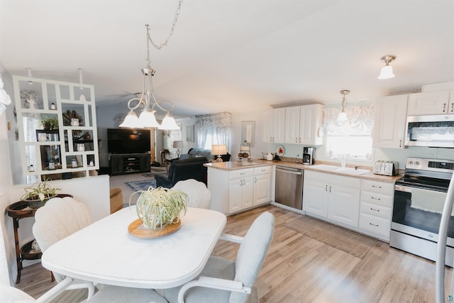 kitchen featuring white cabinets, sink, hanging light fixtures, light hardwood / wood-style flooring, and stainless steel appliances