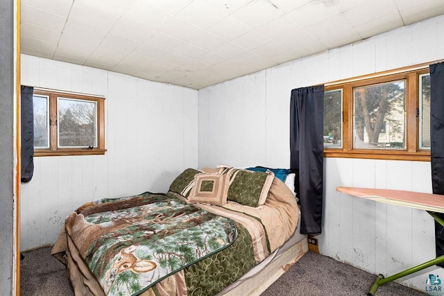 carpeted bedroom with wood walls