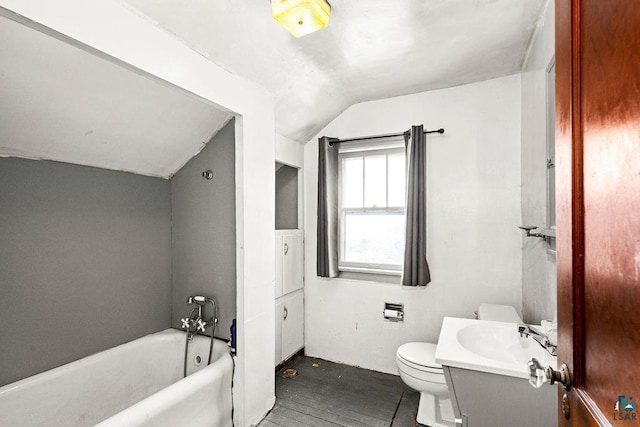 bathroom featuring a washtub, lofted ceiling, toilet, vanity, and hardwood / wood-style flooring