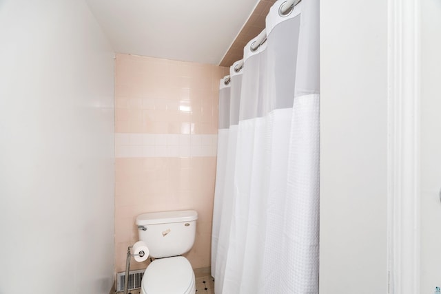 bathroom with a shower with shower curtain, toilet, and tile walls